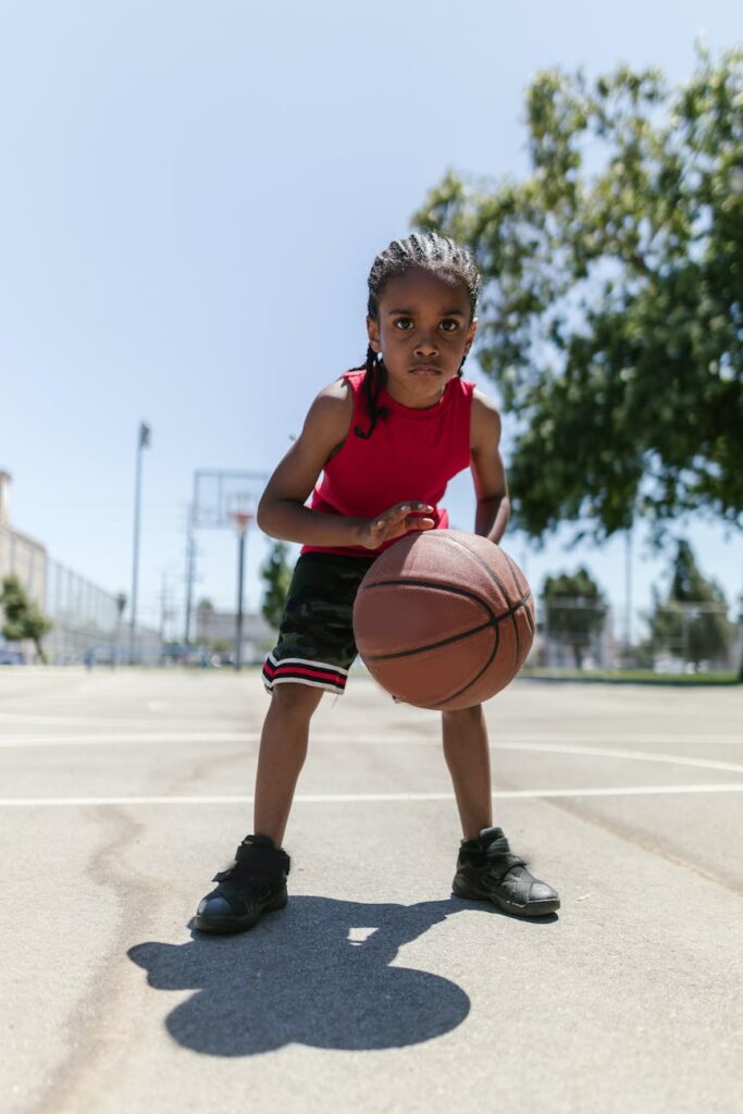 boy wearing a red jersey dribbling a ball