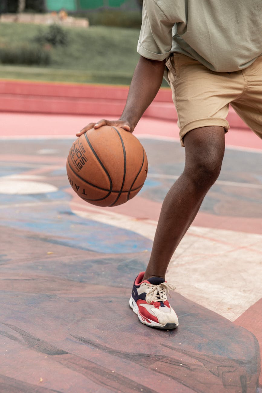 crop anonymous black man dribbling basketball ball on court